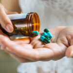 Woman's hand pours the medicine pills out of the bottle