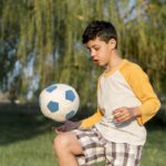 Adolescente jugando fútbol al aire libre